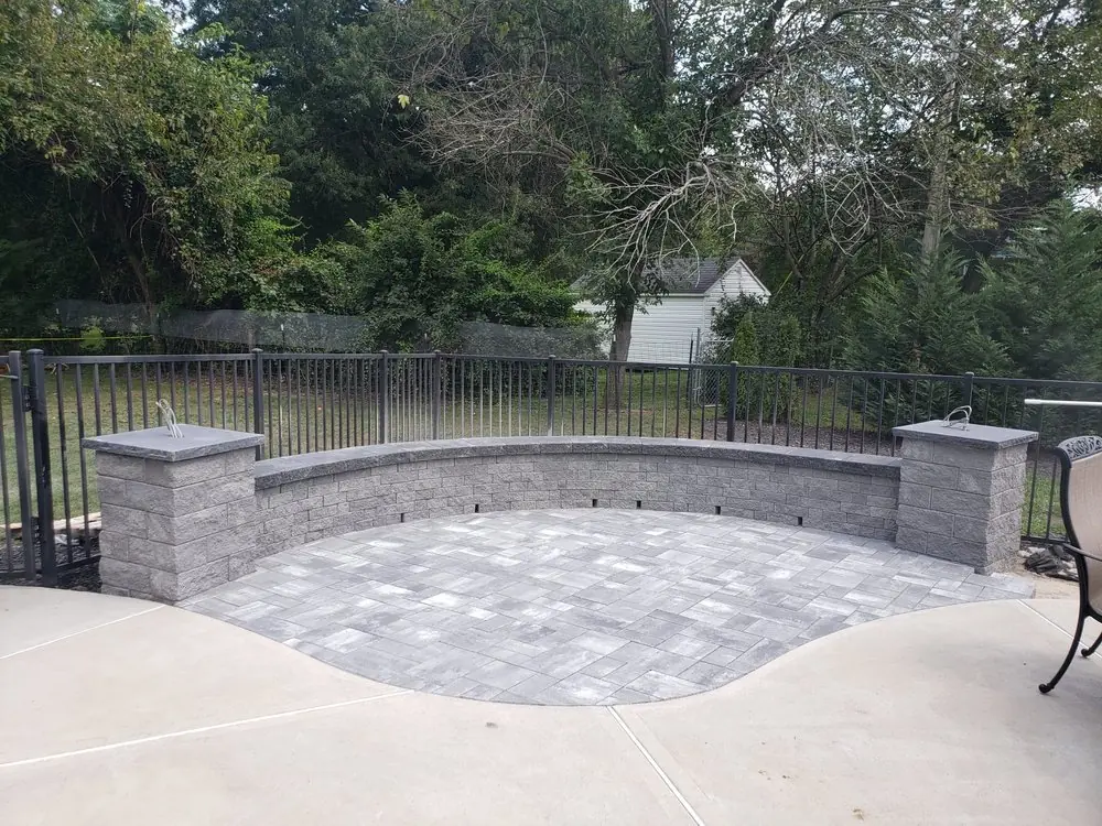 Paver patio with a seat wall and pillars built by Amazing Pavers